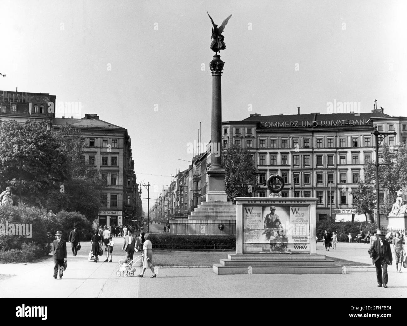 'View of Belle Alliance Square (today's Mehring Square) with the Peace Column in Berlin on 13 May 1943. Friedrichstrasse in the background. On the left of Friedrichstraße facade advertising by Persil, on the right by Commerz- und Privatbank. In front of the Peace Column, posters of the Winter Relief Organization hang on a notice board of the Gau Berlin with the slogans of perseverance and appeals for donations: ''When we think of the sacrifices of our soldiers, of their commitment, then every sacrifice of the homeland is completely meaningless and insignificant'', and: ''What the homeland Stock Photo