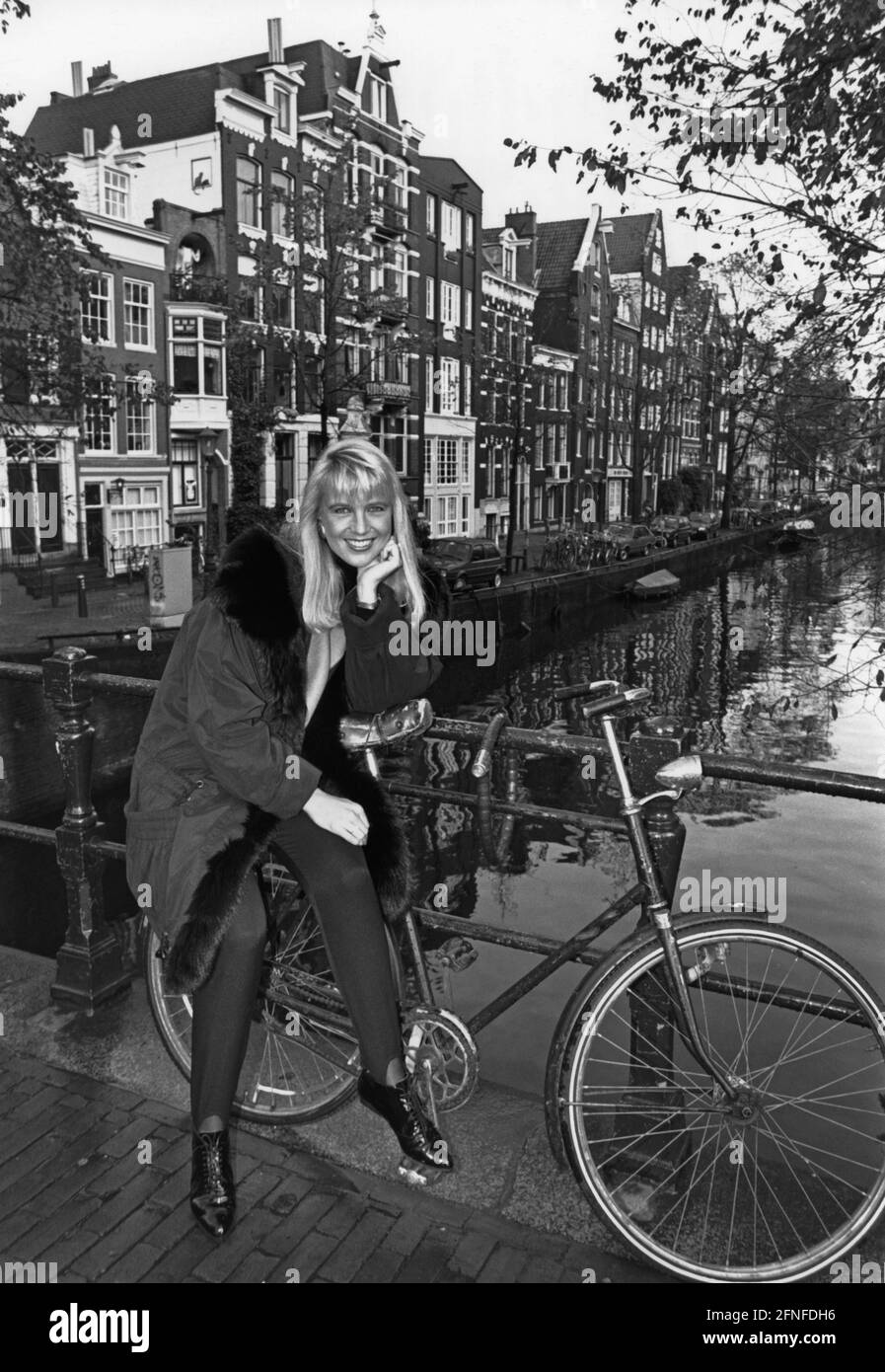 Show host Linda de Mol with bicycle on a bridge in Amsterdam. [automated translation] Stock Photo