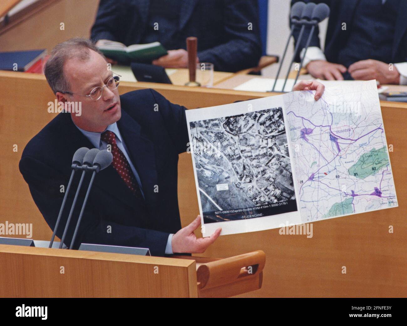 This photograph shows Federal Defence Minister Rudolf Scharping giving a speech at a special session in the Bundestag on the subject of Kosovo. He also shows photos of the devastation in Kosovo. The reason for this speech was the Kosovo conflict, which lasted from 28.2.1998 to 10.6.1999. This armed conflict was about the control of Kosovo, among the different parties were the Kosovo Liberation Army, the Yugoslav Army, Serbian forces of order, as well as NATO forces led by the USA. Kosovo was previously a province of Serbia with a majority Albanian population within Yugoslavia. [automated Stock Photo