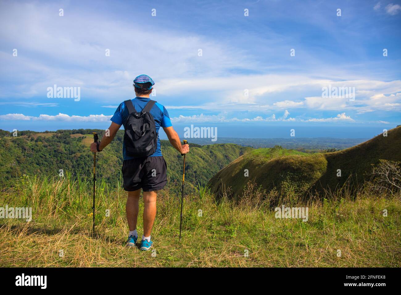Trekker with backpack on the top of hill on natural mountain landscape. Tourist travels through the mountains. Photos of holidays in beautiful places. Stock Photo