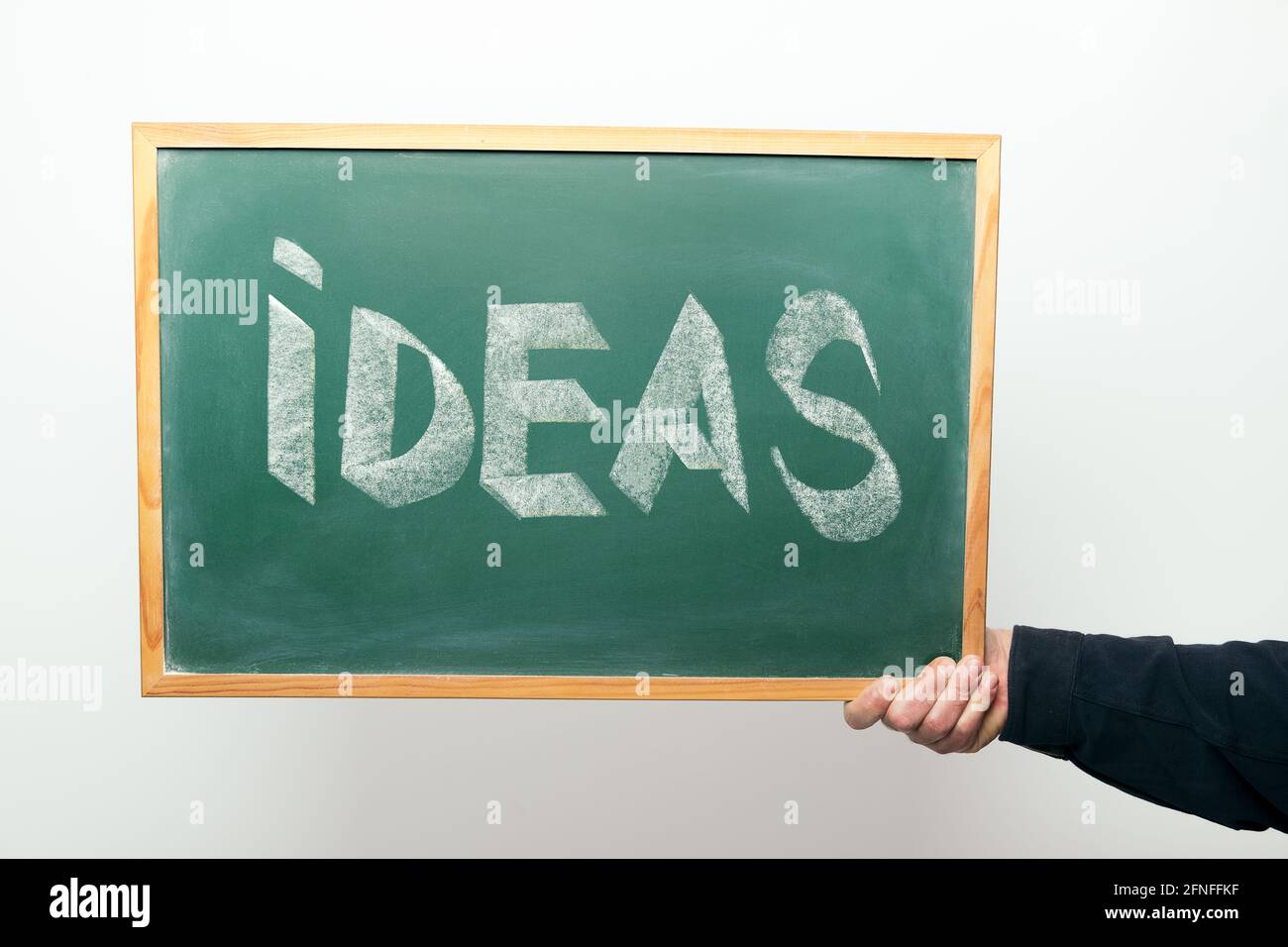 hand holding a chalkboard with the word IDEAS handwritten in chalk ...