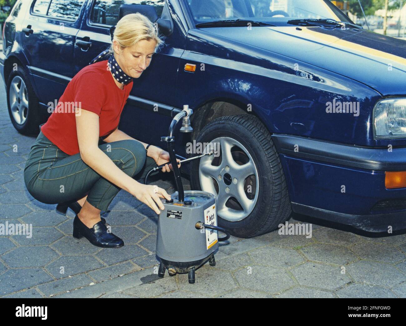 A woman checks the air pressure of the tires of a VW Golf III. [automated translation] Stock
