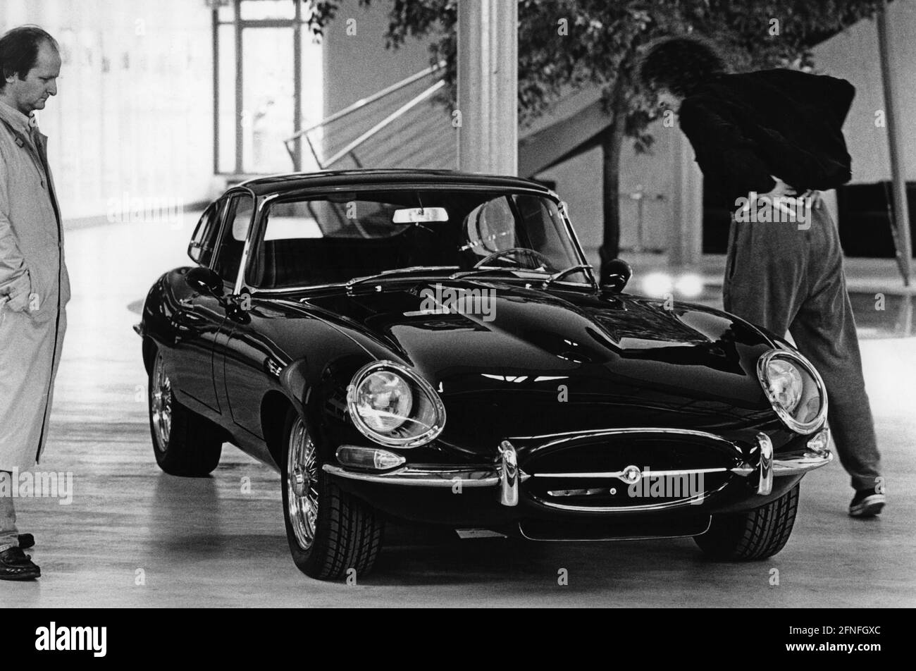 Two men look at a Jaguar E-Type Coupé (XK-E) of the first series. Today, the E-Type is a sought-after collector's item among classic car fans. A vehicle from the first series can be recognised by the Plexiglas covers over the headlights. [automated translation] Stock Photo