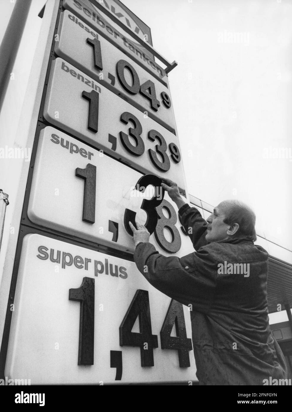 A gas station attendant changes the price tags at a gas station in