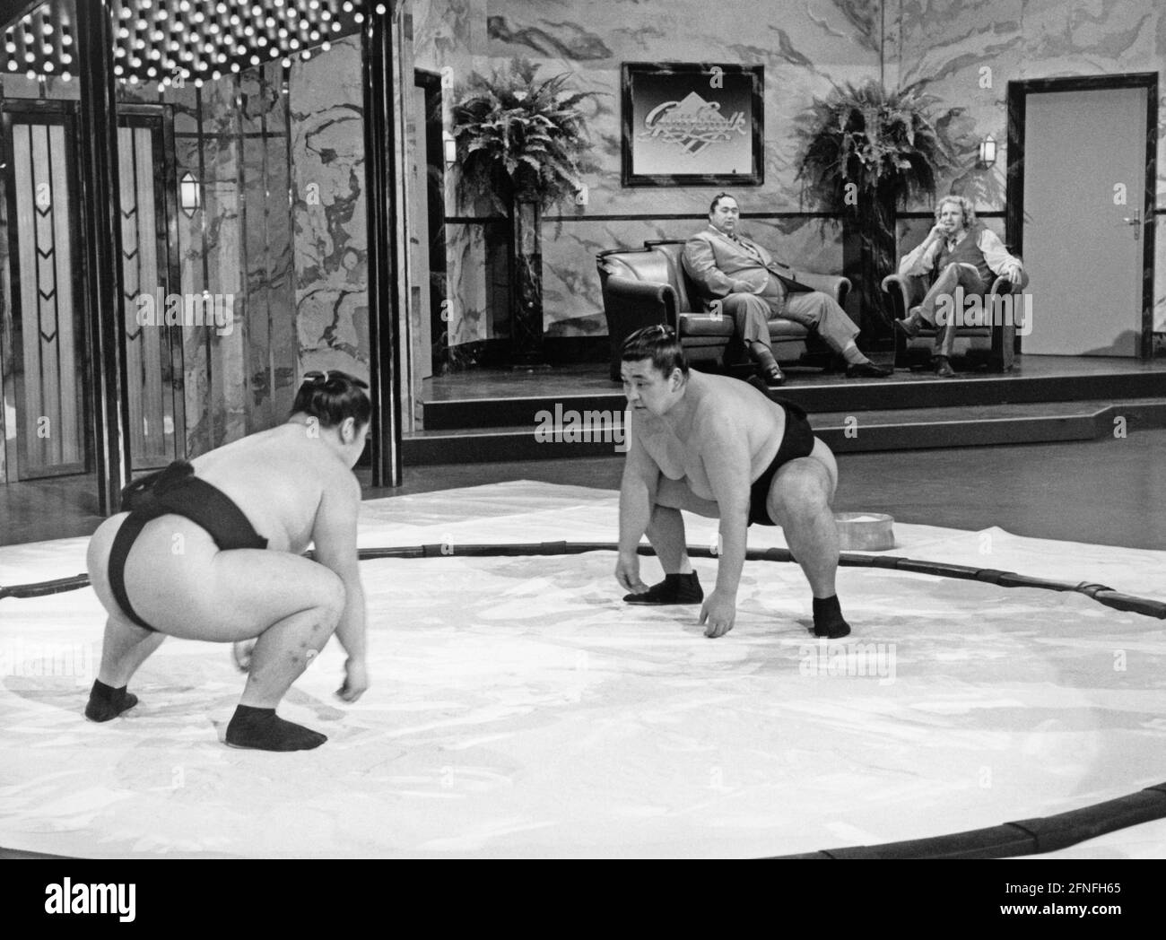 'Two sumo wrestlers face each other in a makeshift ring, ready to fight on the show ''Gottschalk''. Sumo grandmaster Onokuni and Thomas Gottschalk sit in the background. [automated translation]' Stock Photo