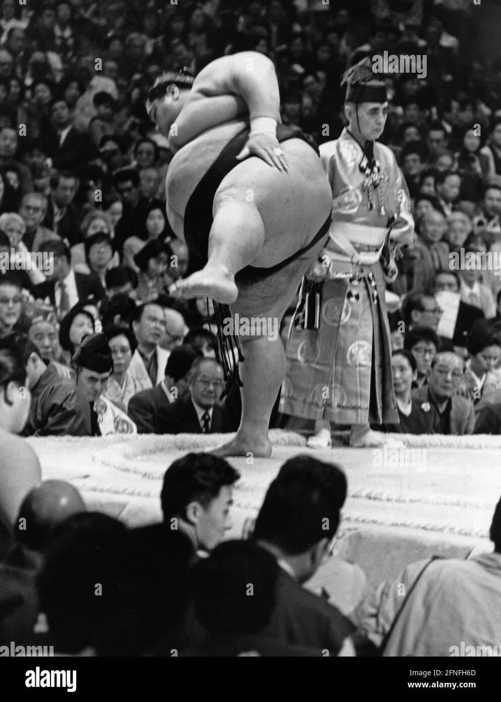 A sumo wrestler performing dohyo-iri, the ring-entering ceremony in Osaka. Next to him is the gyoji, one of the judges. In the background are the spectator stands. [automated translation] Stock Photo