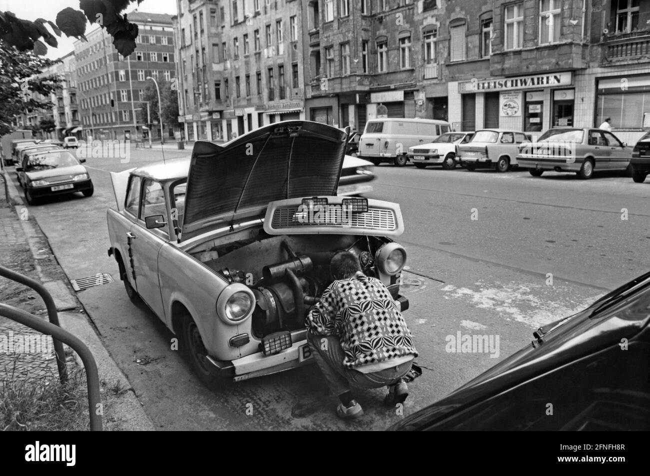 A man repairs his Trabant 601 on the side of a street in Berlin-Prenzlauer Berg. In order to be able to reach the engine more easily, the radiator hood of the Trabant could simply be removed. [automated translation] Stock Photo