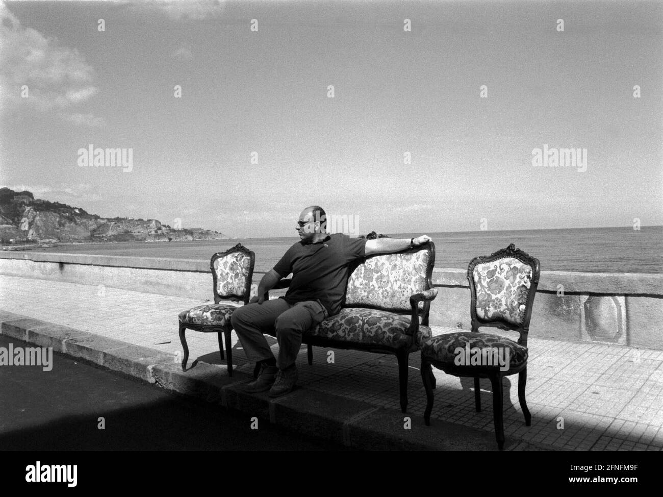 Antique market on the promenade at the beach of Giardini Naxos, man on sofa in front of the sea, Italy, Sicily, 26.05.1999, [automated translation] Stock Photo