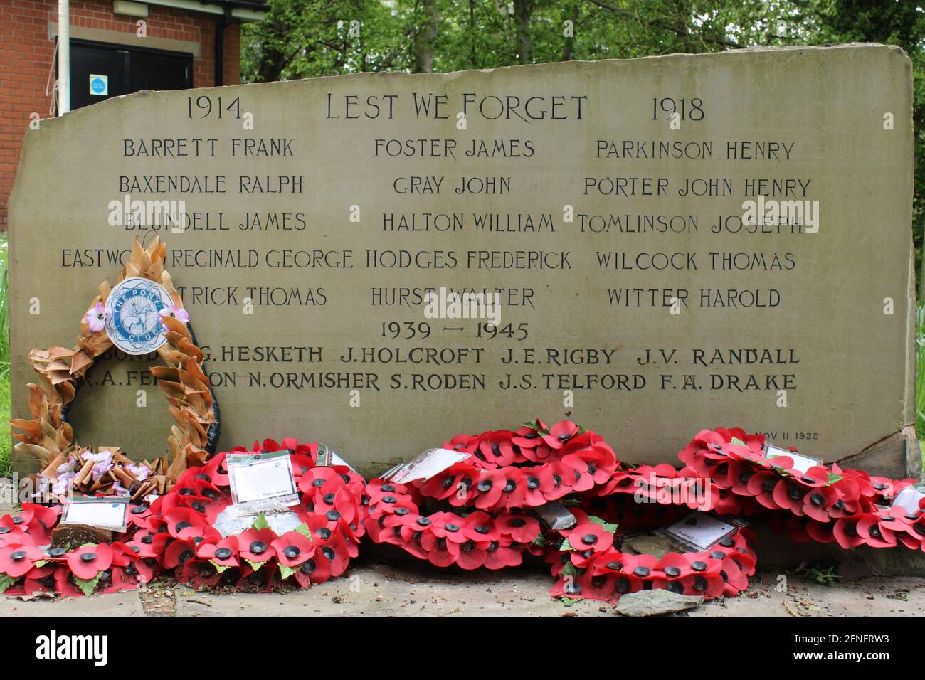 :WW1 and WW2 memorial, Rough hewn stone with dressed face with incised dedication and names and poppy wreath lying at th Stock Photo