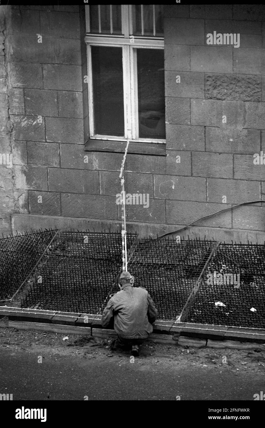 Berlin / Neukoelln / GDR / 24.10.1980 Bouchestrasse. GDR border guards pull new barbed wire along the wall between Neukoelln and Treptow and lay spiked mats along the houses so that no one can jump out of the windows and flee to West Berlin. West Berlin is on the right, the houses belong to East Berlin // GDR Wall / Berlin Wall / Districts / History / Communism The GDR border guards mostly belonged to the Stasi, even if they wore uniforms of other units of the People's Army. [automated translation] Stock Photo