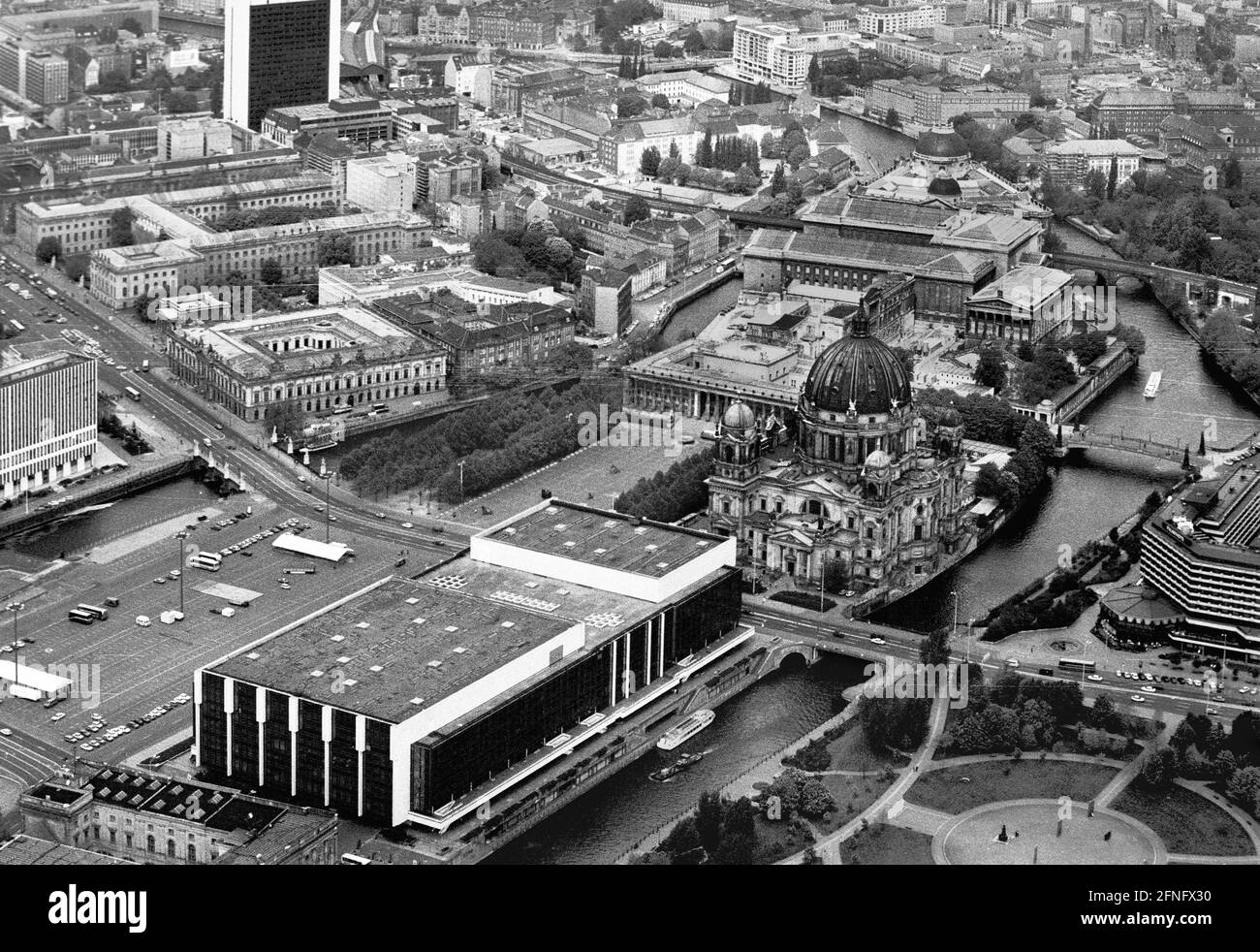 Berlin-City / GDR / 5 / 1991 The Palace of the Republic at the Schlossplatz, on the right Museum Island, on the left Unter den Linden, in front the river Spree // Mitte / Stadtschloss // Parliament /Unter den Linden / History In place of the City Palace, which was demolished in 1950, the Palace of the Republic was built from 1973 on, 180 m long, 32 m wide. In it were various facilities. In the large hall events took place, it held 5000 visitors. In the small hall the GDR chamber of people met. There were also restaurants and cafes for 1500 guests. From 2016 the new building is called Stock Photo