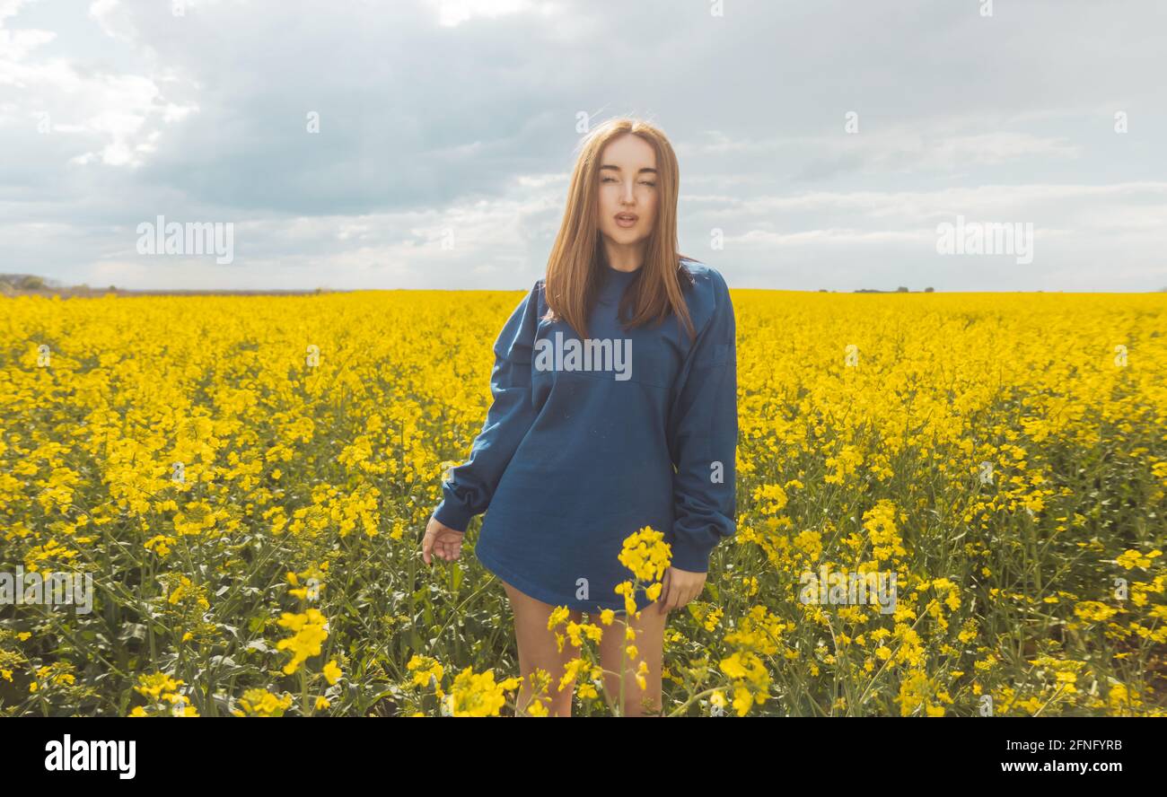 beautiful girl in blue hoodie in yellow field Stock Photo - Alamy