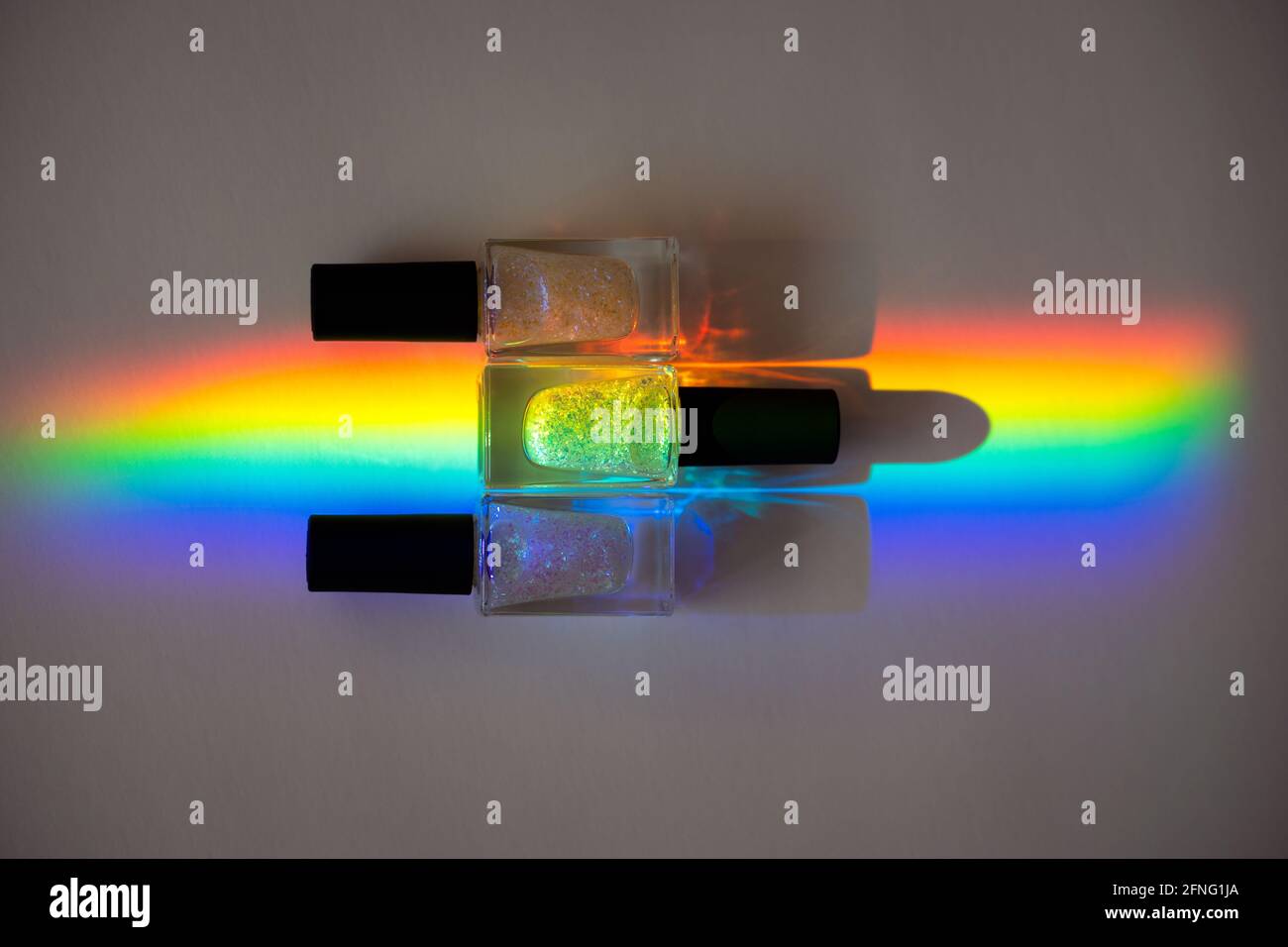 Holographic Nailpolishes in a prism rainbow line on a grey paper Stock Photo