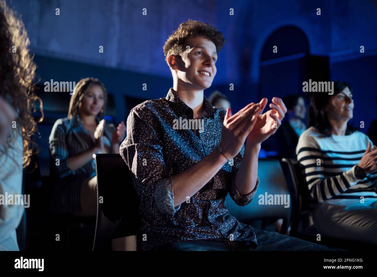 Group of people clapping while listening to presentation at conference. Stock Photo
