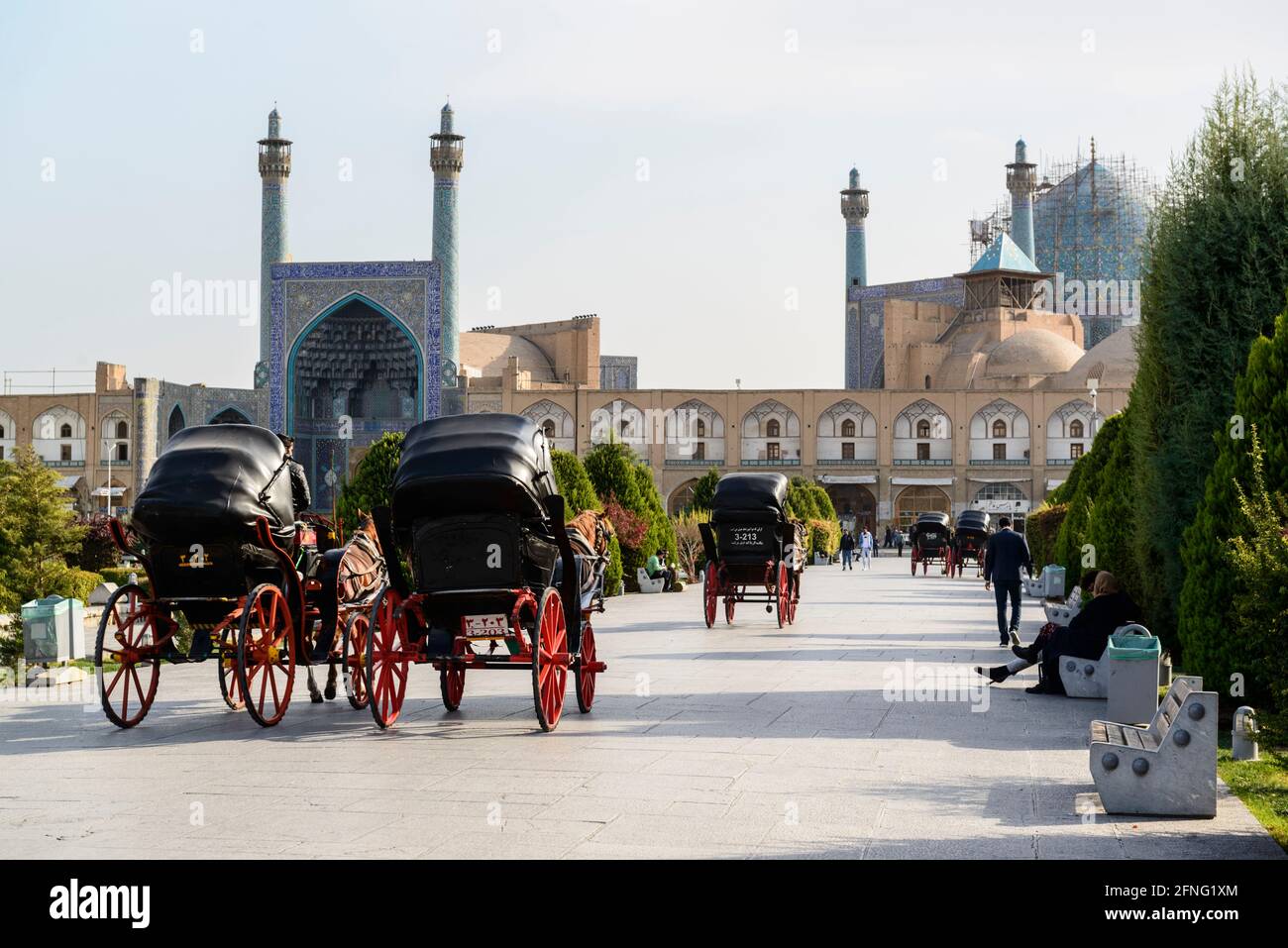 Horse-drawn carriages driving around with tourists on the Naqsh-e Jahan Square. Shah Mosque in the background. Isfahan, Iran. Stock Photo