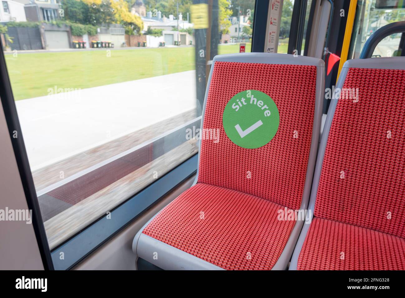 A big green tick sticker or decal on a seat in a Sydney Light Rail Tram indicates a safe place to sit during the Covid-19 pandemic in Australia Stock Photo