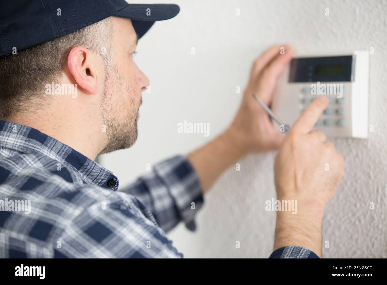 male contractor programming electronic keypad on the wall Stock Photo