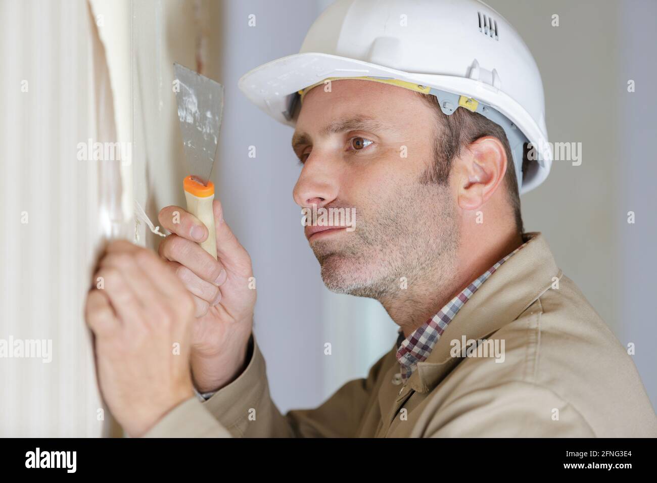 professional male stripping wallpaper with a scraper Stock Photo - Alamy
