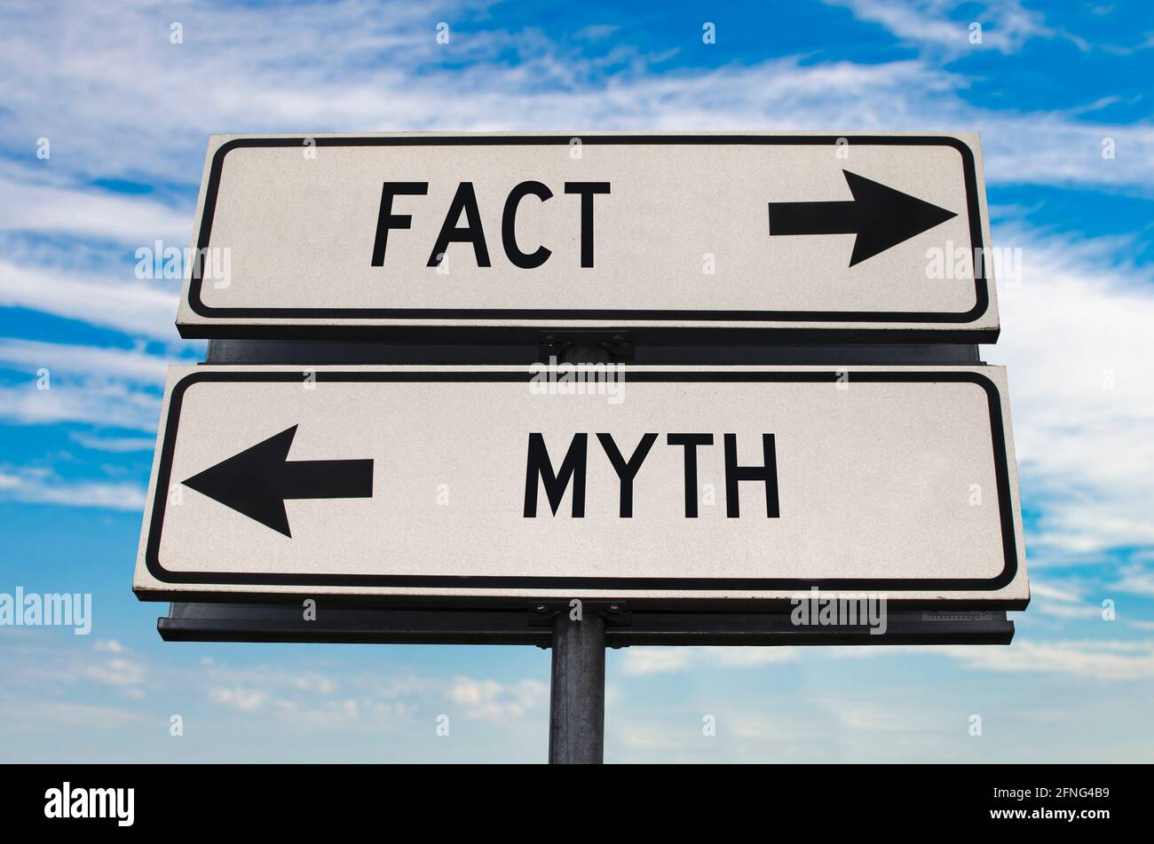 Fact versus myth road sign with two arrows on blue sky background. White two street sign with arrows on metal pole. Two way road sign with text. Stock Photo