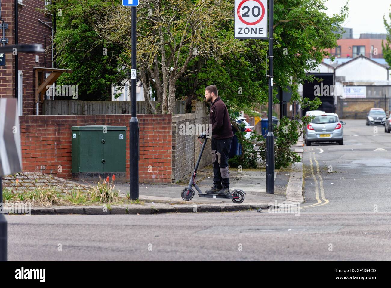 A young white male riding an electric scooter on the pavement in