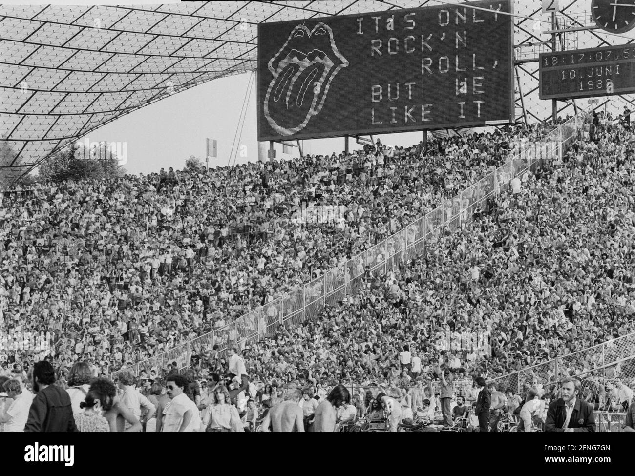 Fans at the Rolling Stones concert in the rows of spectators at the  Olympiastadion in Munich. In the background is a big board with the  inscription ""Its only Rock n Roll, but