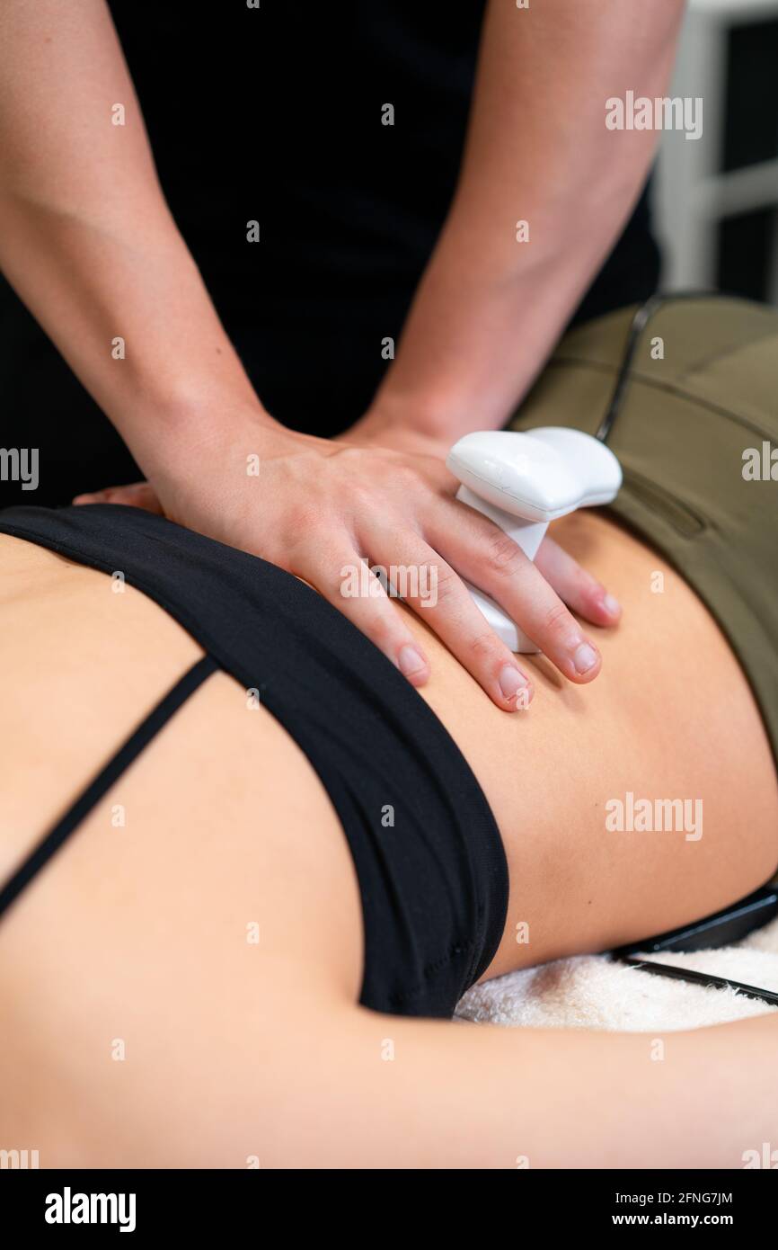 Male physiotherapist applying laser to back skin of female during medical treatment in hospital Stock Photo