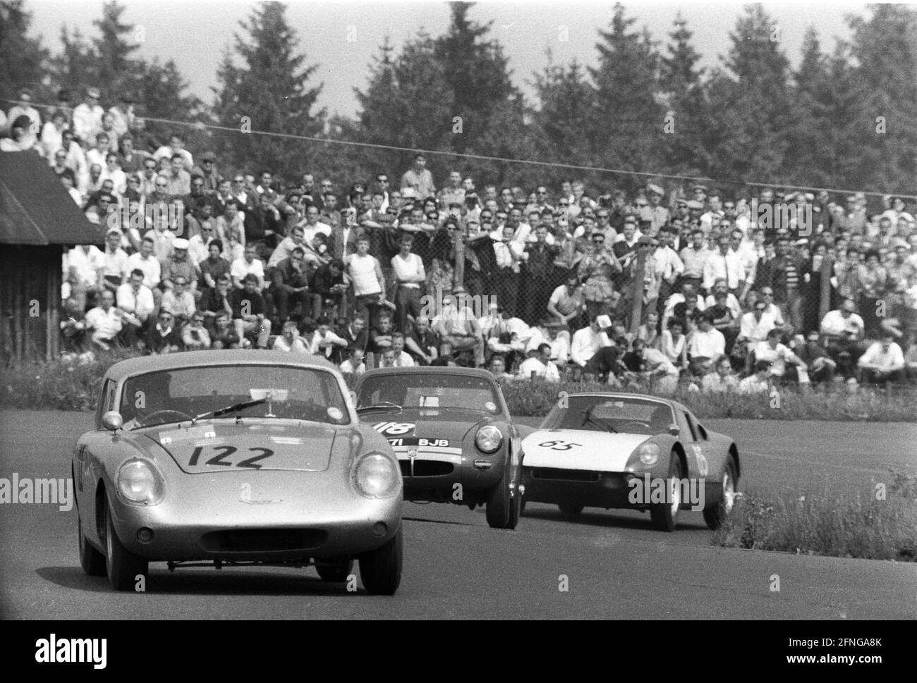1000km race on the Nürburgring 31.05.1964. In front an Austin Healey Sebring Sprite (No. 122) , MG Midget (No. 118) and a Porsche 904 GTS (No. 65). In the background many spectators , separated only by a fence. [automated translation] Stock Photo