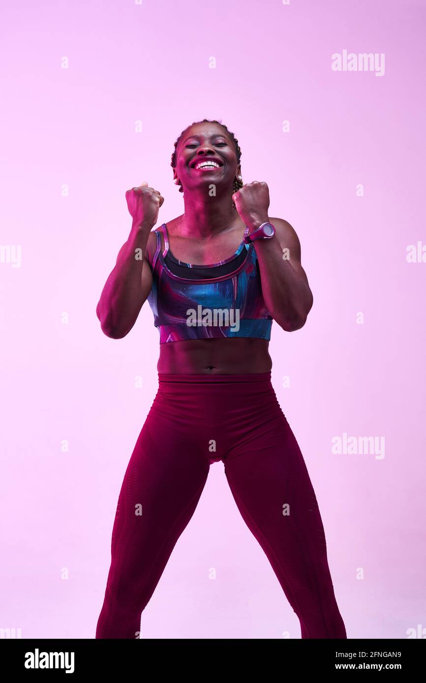 African American sportsWoman in activewear demonstrating win gesture while looking at camera with toothy smile Stock Photo