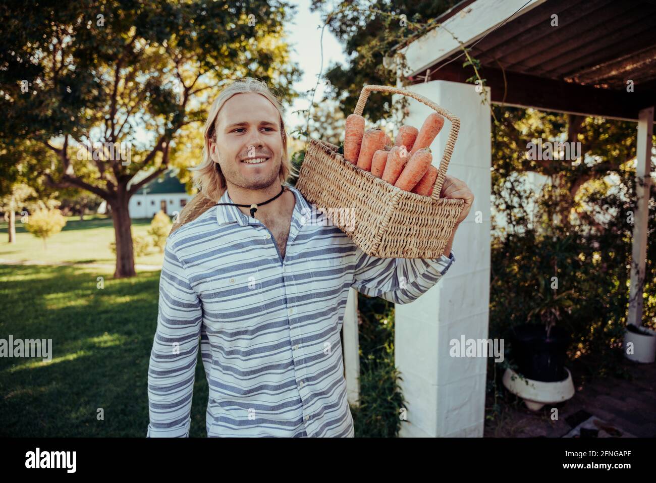 Caucasian male walking through farm village after picking fresh vegetables from garden  Stock Photo
