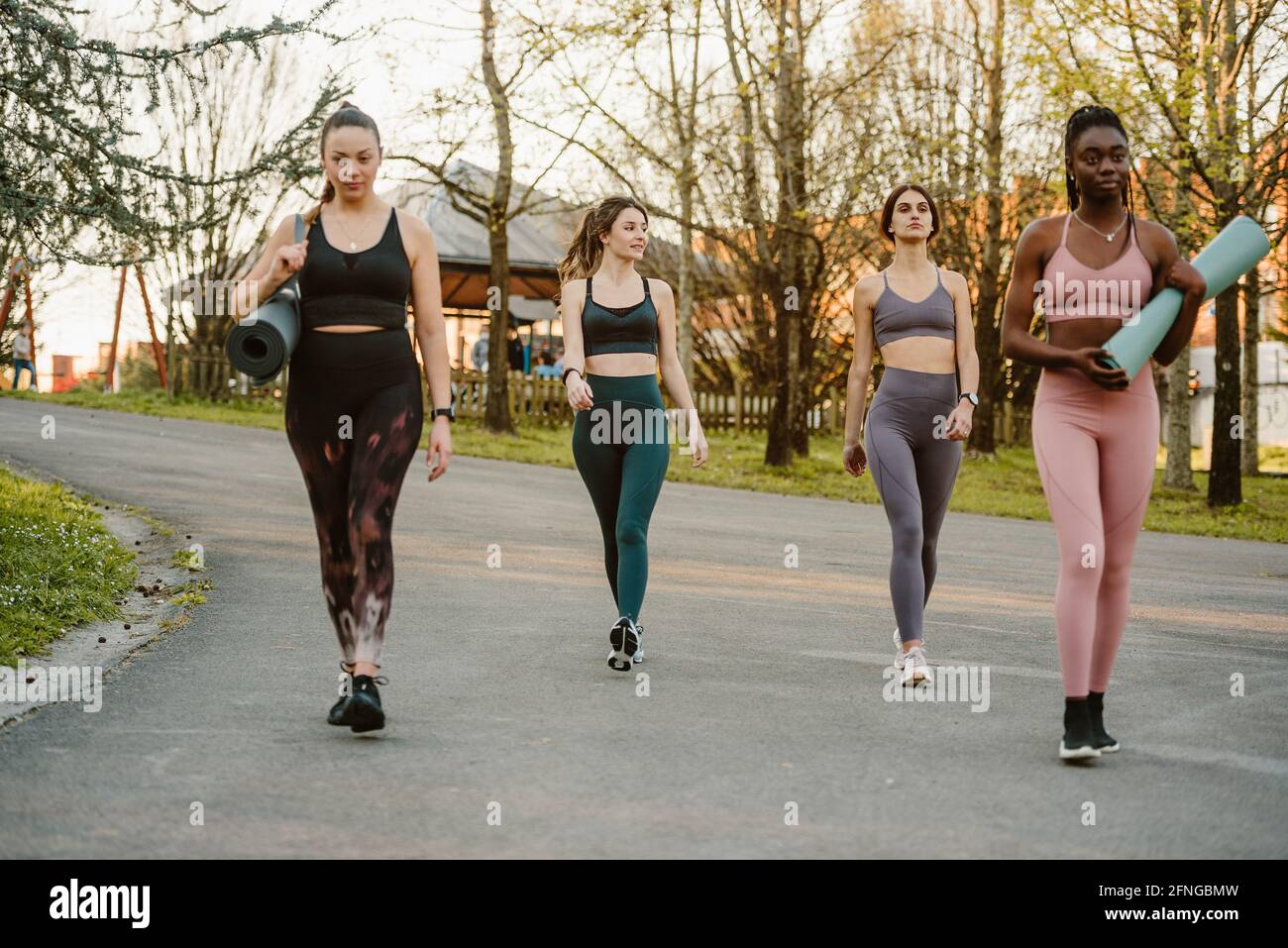 Company of multiracial female athletes in leggings and bra walking along street for training in summer park Stock Photo Alamy