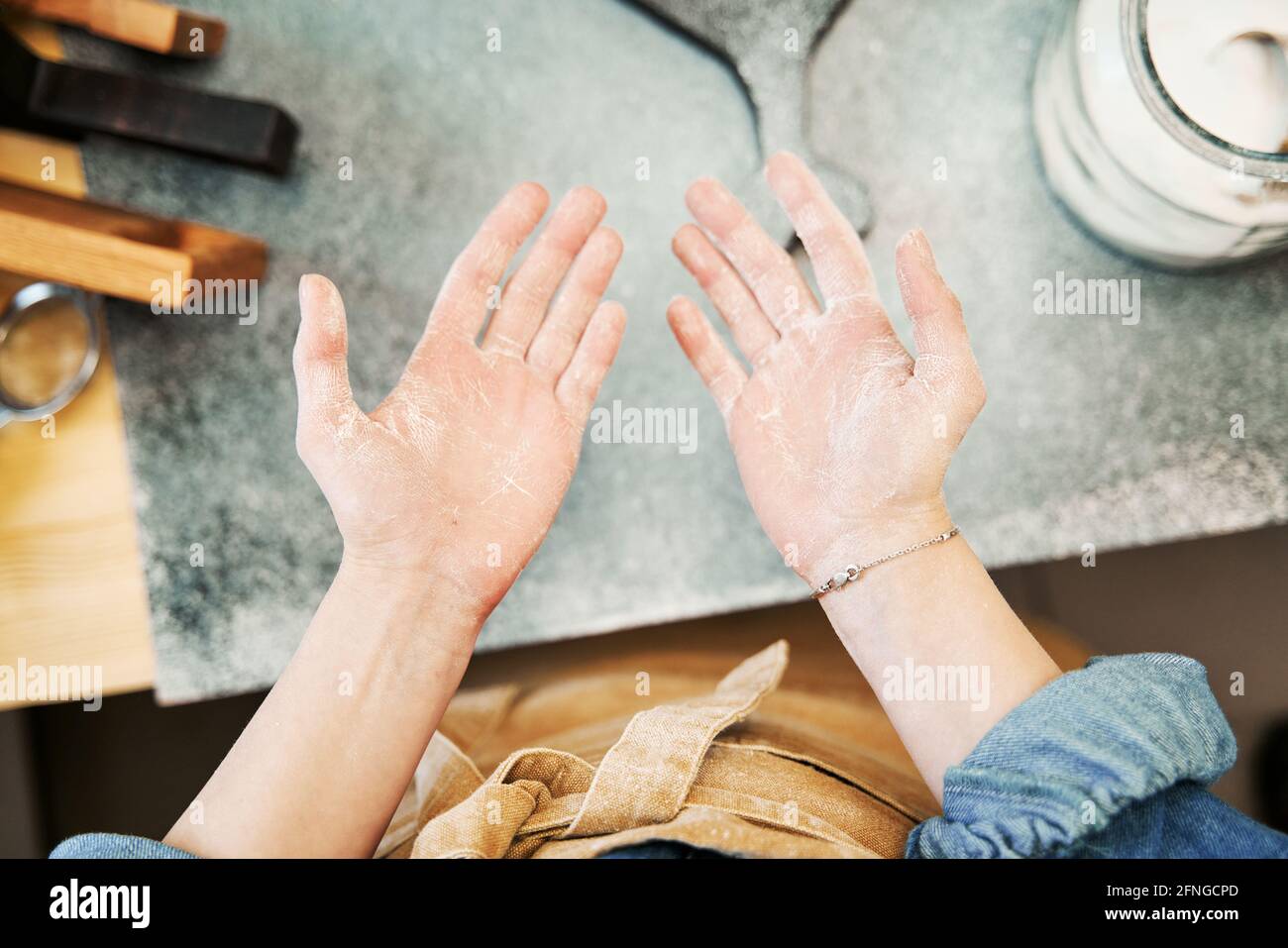 Crop unrecognizable female in apron showing palms of hands with flour ...