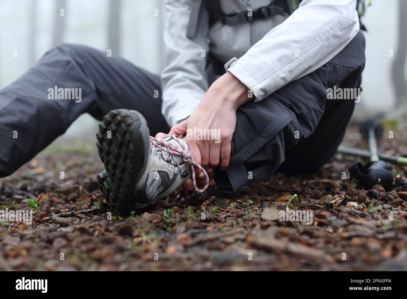 Close up of a stressed trekker complaining alone in the mountain with broken ankle Stock Photo