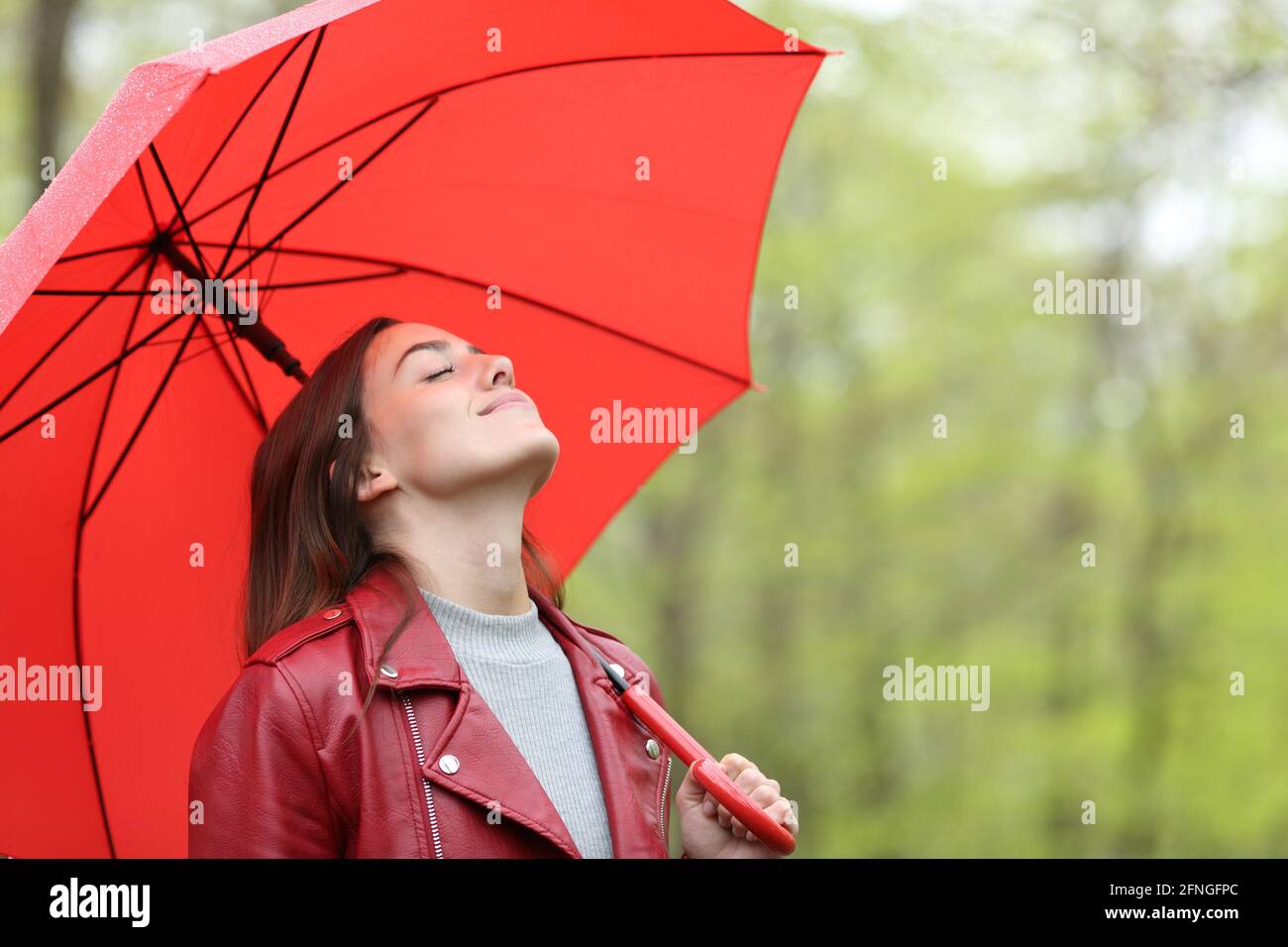 Happy woman breathing fresh air under red umbrella in a park Stock ...
