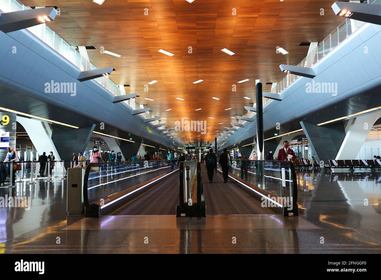 Doha, Qatar – May 12, 2021: Hamad International Airport interior with autowalk flat escalator at departure terminal with few passengers due to Covid 1 Stock Photo