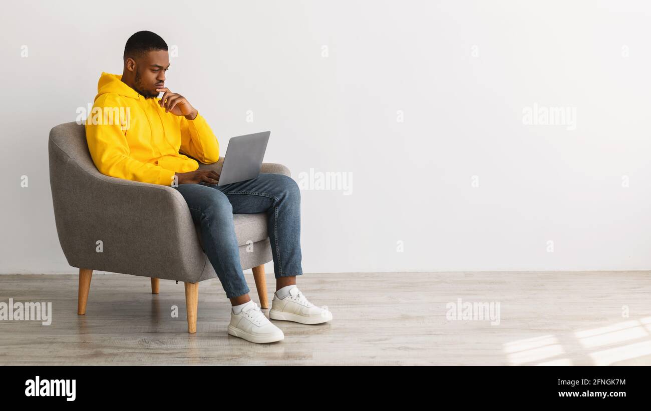 African American Man Using Laptop Thinking Working Online, Gray Background Stock Photo