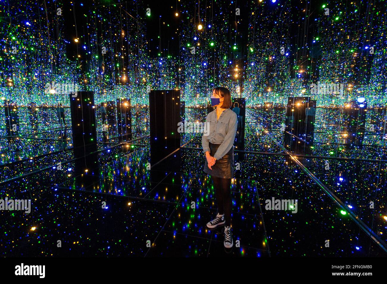 London, UK.  17 May 2021.A Tate staff member views 'Infinity Mirrored Room – Filled with the Brilliance of Life', 2011, by Yayoi Kusama.  Preview of Yayoi Kusama: Infinity Mirror Rooms on show at Tate Modern, in partnership with Bank of America with additional support from UNIQLO, from 18 May to 12 June 2022.  Credit: Stephen Chung / Alamy Live News Stock Photo