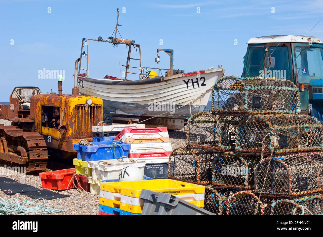 Lobster pots on pebbled beach with ford tractor and fishing boat Stock Photo