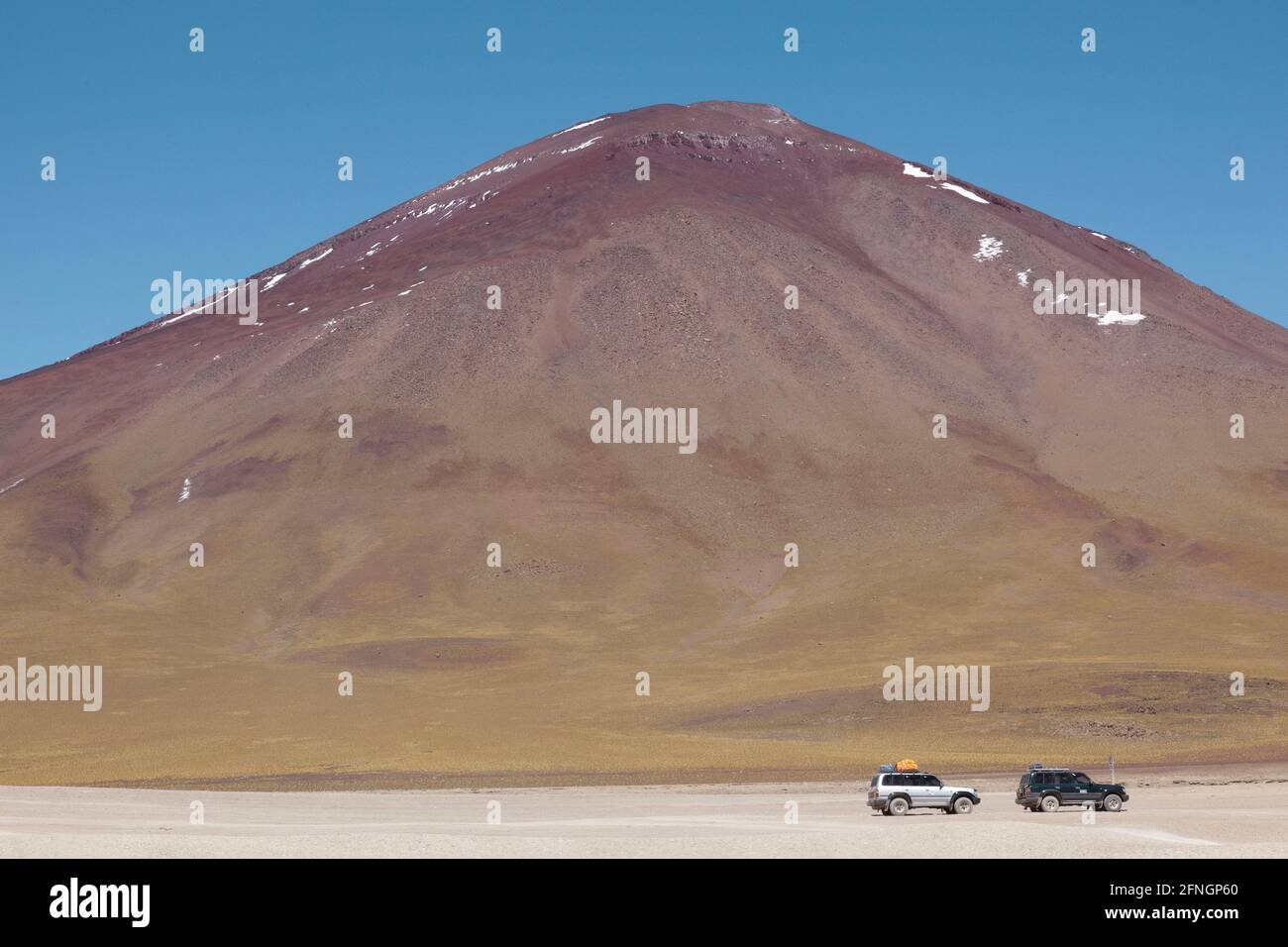 4x4 SUV over-land safari vehicles are seen at the edge of the Laguna Verde in the Bolivian desert. Stock Photo