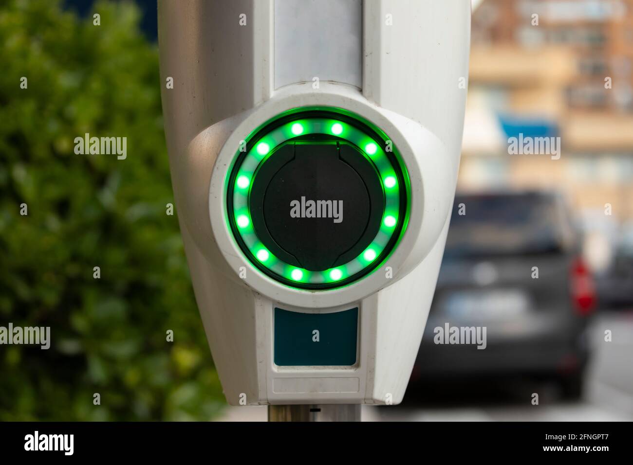 A battery charging point for electric cars, illuminated with green LEDs, in the area of the