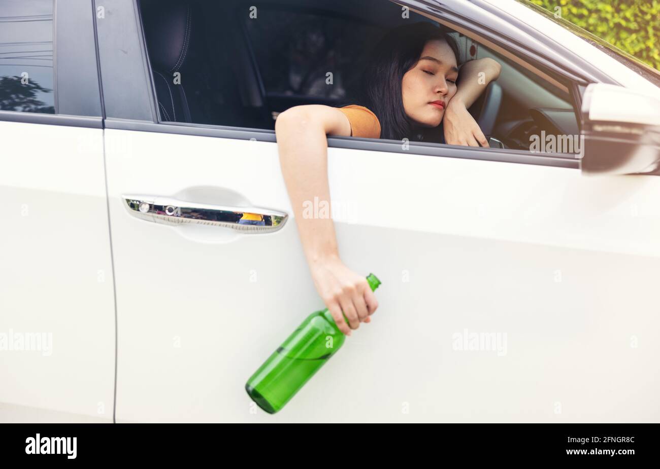 woman drinking from a beer bottle while driving car, a concept of
