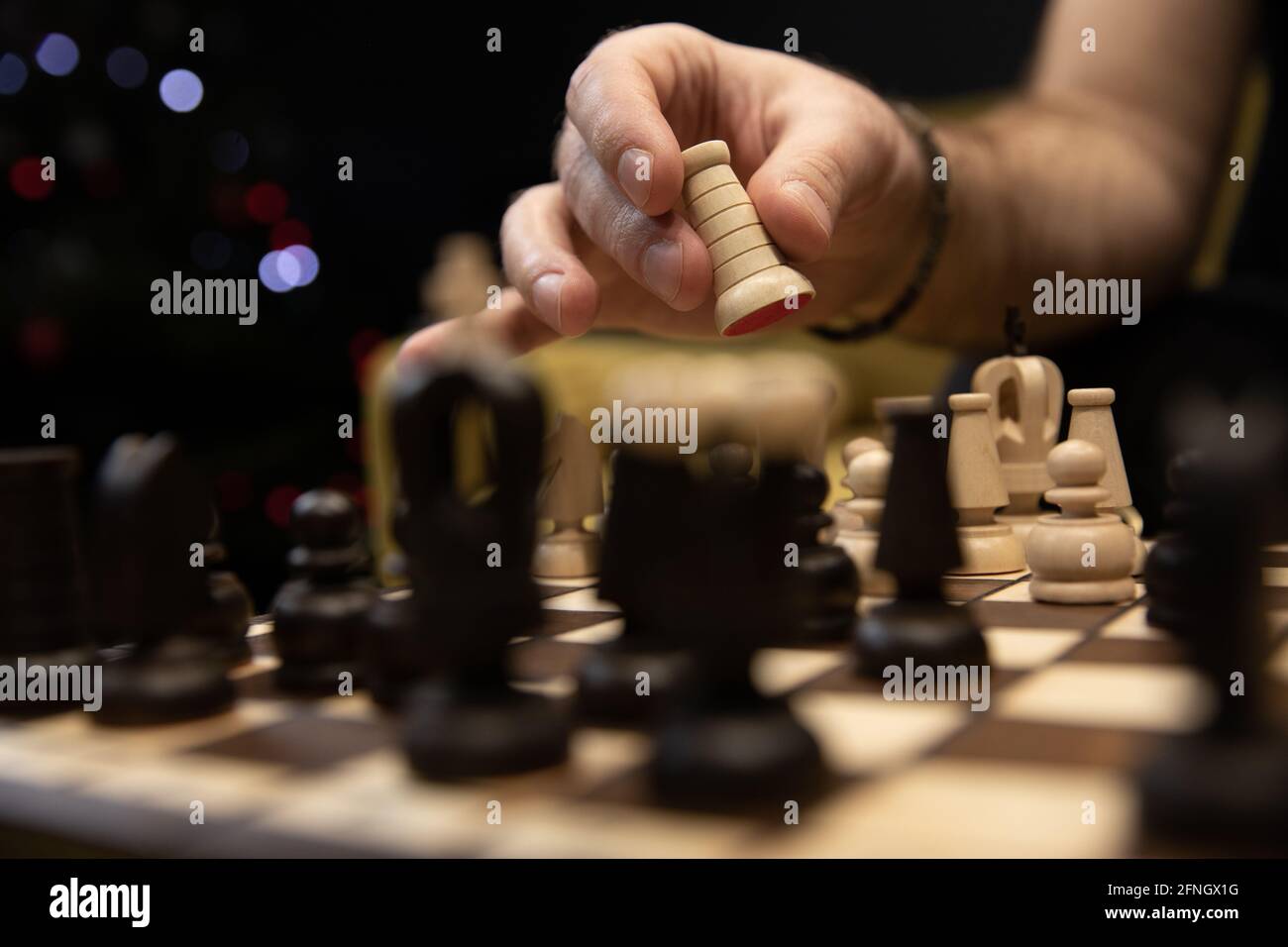 Hand taking next step on chess game. Human hand moving wooden white rook piece Stock Photo