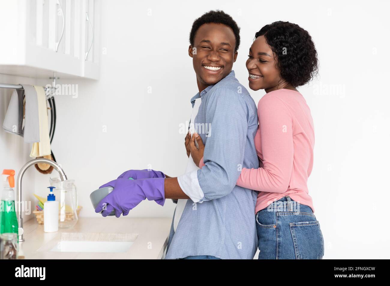 Black woman hugging her husband washing dishes Stock Photo - Alamy