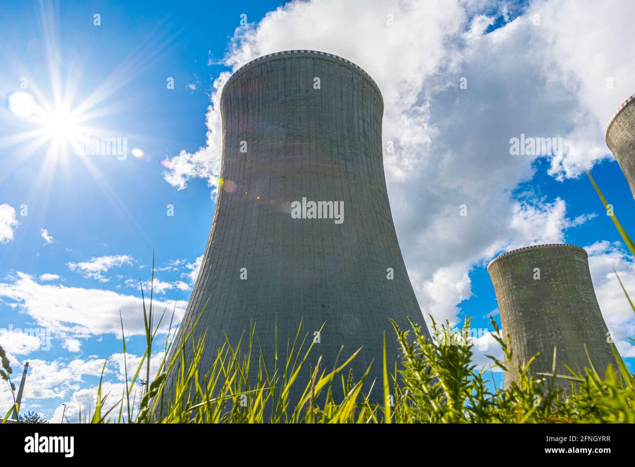 Close-up shot of a cooling tower of nuclear power plant behind green grass. In a beautiful sunny day. Stock Photo
