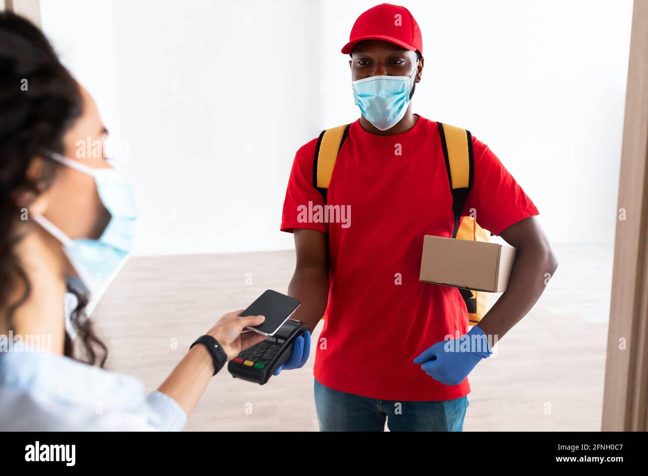 Black man holding POS machine client paying with smart phone Stock Photo