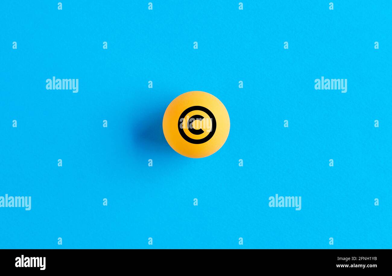 Copyright icon on yellow ball on blue background. Property and intellectual rights protection. Stock Photo