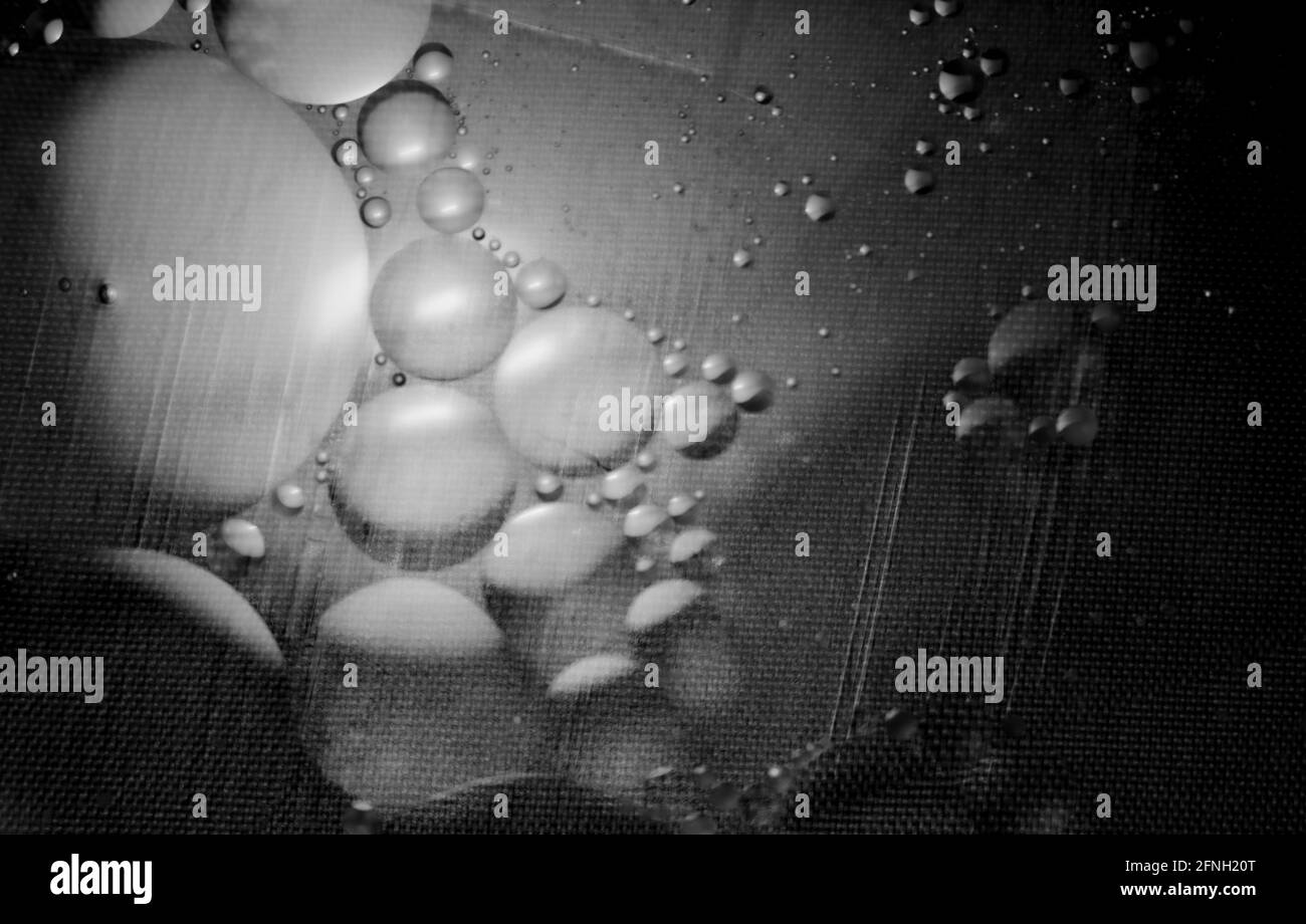 Black and white oil and water agitated to make bubbles with light shining through the liquids Stock Photo