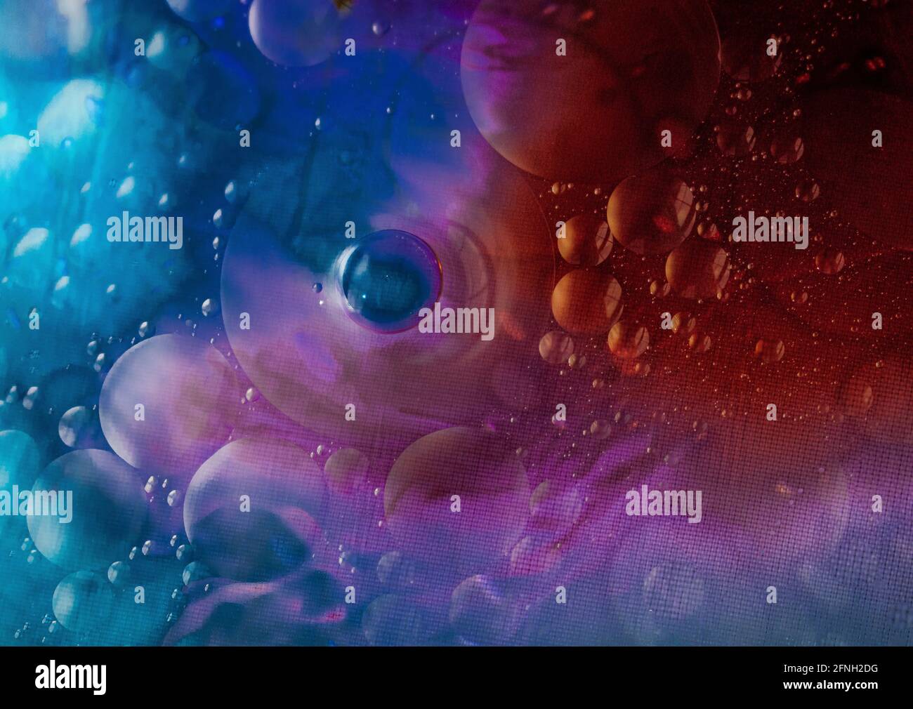 Oil and water agitated to make bubbles with light shining through the liquids Stock Photo