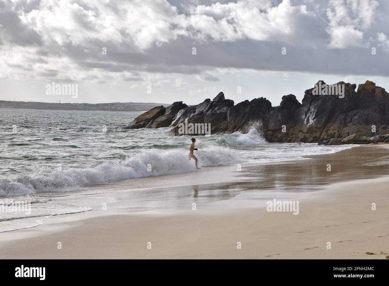 Morning view of porthgwidden beach on a cloudy day with a woman emerging from the water after swimming with bikini and gloves Stock Photo