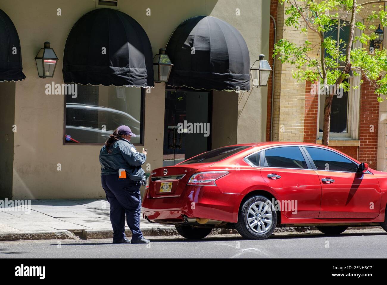 NEW ORLEANS, LA, USA - APRIL 21, 2021: Parking control officer writes a ticket for an illegally parked car Stock Photo