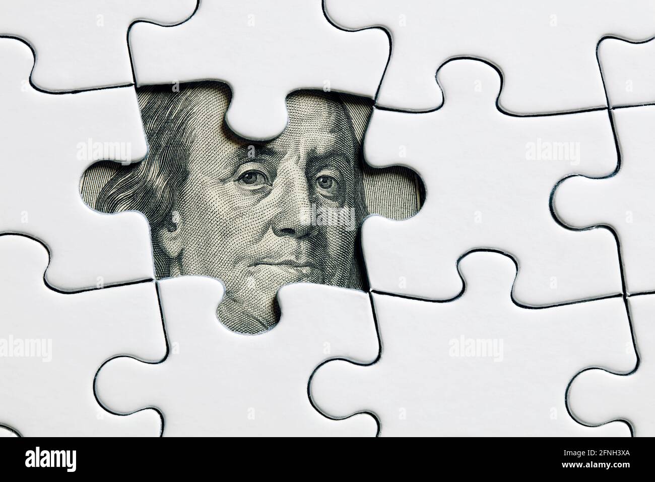 Benjamin Franklin's face from a hundred dollar bill between assembled puzzle pieces. Economic or financial turmoil, uncertainty or devaluation. Stock Photo
